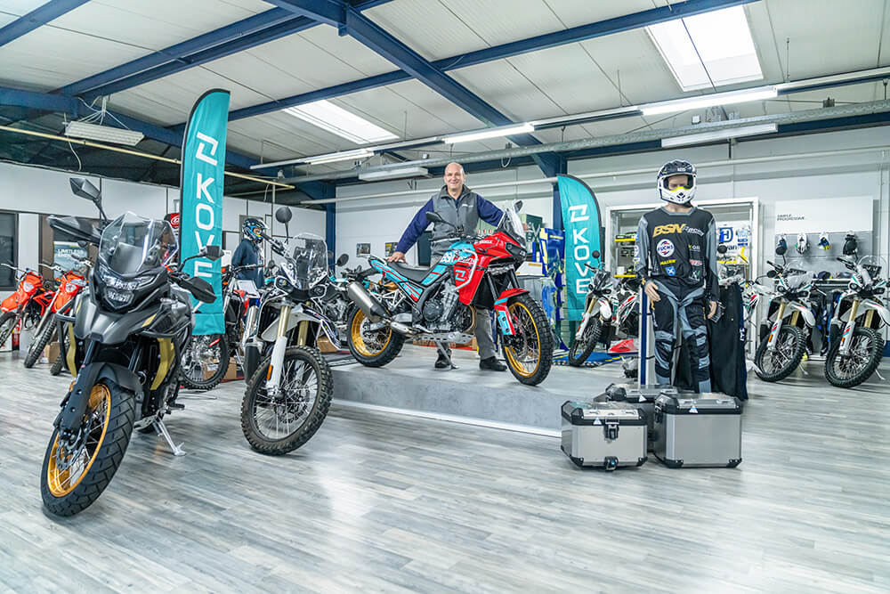 Thorsten Vulpius, Chef von BSN-Racing vor einer Kove 450 Rally im Laden umgeben von anderen Motorrädern