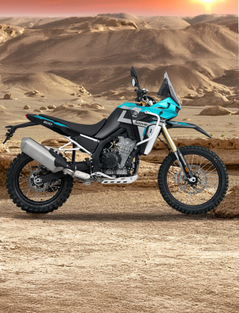 Seitenansicht der Kove 800X Rally in blau in einer bergigen Wüstenlandschaft mit rotem Sonnenuntergang