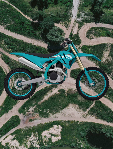 Kove Motorrad MX450 Seitenansicht, im Hintergrund eine Motocross-Strecke aus der Vogelperspektive